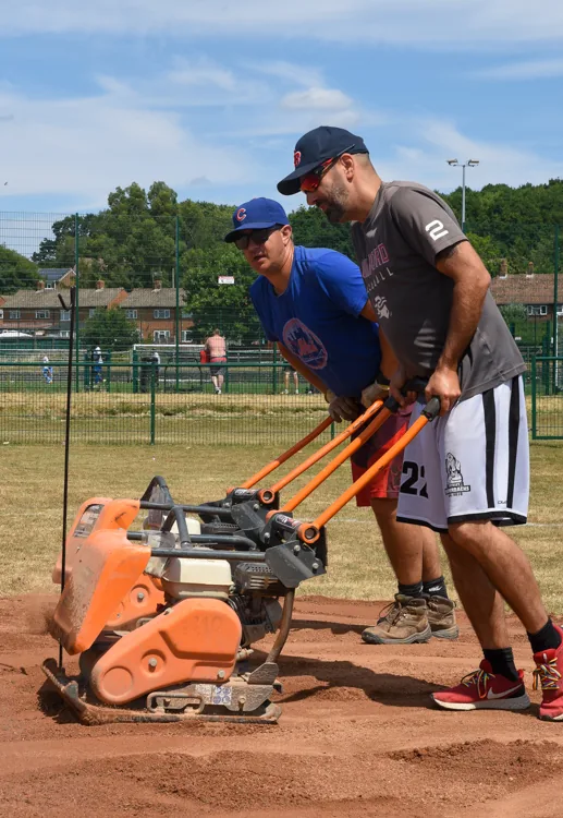Two members compacting the new infield dirt