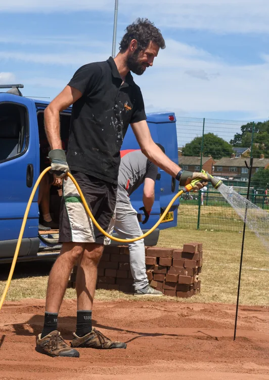 A member watering the fresh clay