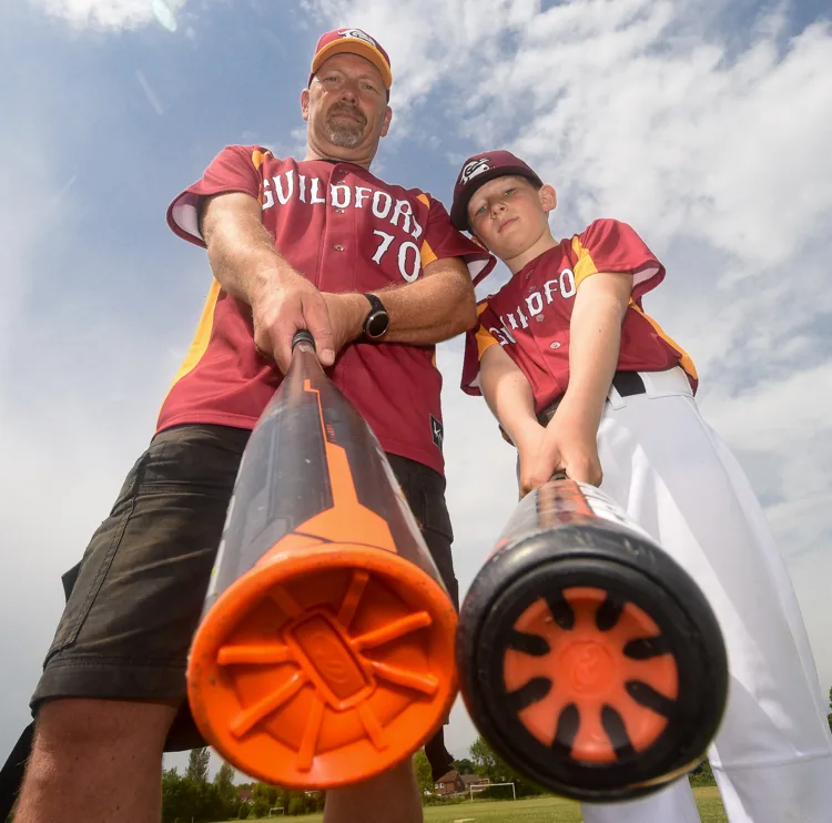 A coach and a young player grinning with their bats at junior pre-season training